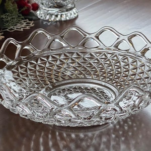 May include: Clear glass serving dish with a diamond pattern and a decorative, openwork rim. The oval-shaped dish is designed for serving food or displaying decorative items. The dish is made of clear glass.