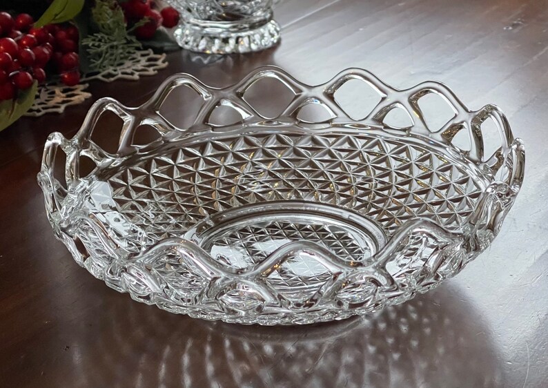 May include: Clear glass serving dish with a diamond pattern and a decorative, openwork rim. The oval-shaped dish is designed for serving food or displaying decorative items. The dish is made of clear glass.