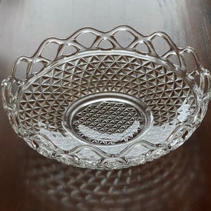 May include: Clear glass serving dish with a diamond pattern and a decorative, openwork rim. The dish has an oval center and a scalloped edge, perfect for serving appetizers or desserts. The glass reflects light, creating a sparkling effect.