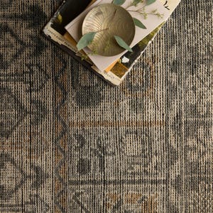 May include: A patterned rug in grey, brown, and black tones. A stack of books with the text "FORTY-EIGHT PAINTINGS REPRODUCTIONS" and a small gold-coloured dish with leaves are placed on the rug, creating a layered effect.