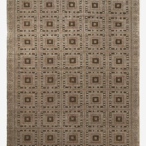 May include: A rectangular brown rug with a repeating geometric pattern of squares and rectangles. The rug has a border with a repeating design and fringe on the short ends. The color palette includes shades of brown and beige.