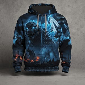 May include: A dark blue hooded sweatshirt featuring a large graphic of a monster with glowing blue eyes and spikes. The design includes lightning bolts, white feathers, and a city scene with fire at the bottom. The hoodie has a drawstring and patterned trim.