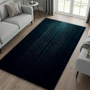 Puede incluir: Una alfombra rectangular con un fondo degradado en verde azulado oscuro y negro. La alfombra presenta un patrón de líneas de código binario blancas. Está colocada sobre un suelo de madera clara, cerca de un sofá gris.