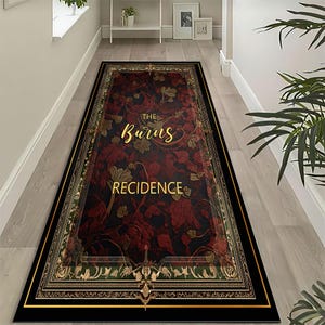 Puede incluir: Una alfombra rectangular con borde negro y ribete dorado. El centro de la alfombra presenta un estampado floral rojo oscuro con las palabras "THE Burns RECIDENCE" en letras doradas. La alfombra está colocada sobre un suelo de madera clara.