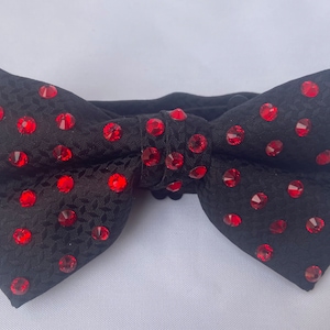 May include: A black bow tie with red rhinestone embellishments.