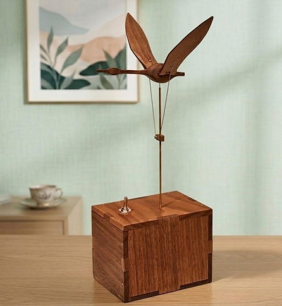 A hand-carved wooden swan automaton that actually moves — kinetic mechanical art meets music box in a single desk-worthy object a real craftsperson built by hand.