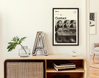 May include: A framed black and white poster with the word "Contact" in bold, white letters. The poster features a collage of images of a woman's face and eyes.