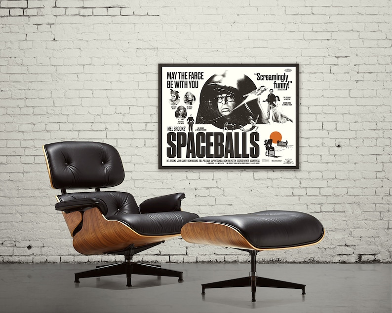 May include: A black and white movie poster for the film "Spaceballs" directed by Mel Brooks. The poster features a character in a black helmet and a quote that reads "May the farce be with you".