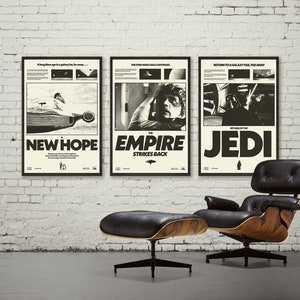 K&ouml;nnte beinhalten: Drei schwarz-wei&szlig;e Star Wars-Filmplakate in schwarzen Rahmen, die an einer wei&szlig;en Backsteinwand h&auml;ngen. Die Poster sind f&uuml;r Star Wars: Eine neue Hoffnung, Das Imperium schl&auml;gt zur&uuml;ck und Die R&uuml;ckkehr der Jedi. Ein schwarzer Ledersessel mit Holzsockel und einem passenden Hocker stehen vor den Postern.