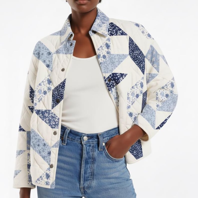 May include: A quilted jacket with a patchwork design in white, light blue, and navy blue. The jacket has a button-down front, a collared neckline, and long sleeves. The design incorporates floral and geometric patterns.