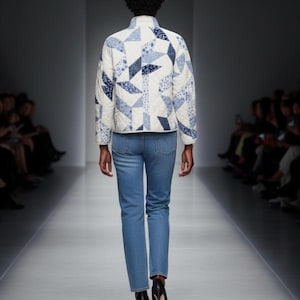 May include: A quilted jacket with a geometric pattern in shades of blue and white, paired with light blue jeans. The jacket features a stand-up collar and a quilted design. The model is walking on a runway.
