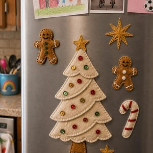 May include: A set of felt Christmas-themed magnets on a refrigerator, including a cream-coloured tree with colourful sequins, two brown gingerbread people with white stitching, a gold star, and a white candy cane with red stripes.