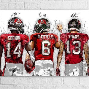 May include: Artwork featuring three football players in red jerseys with white numbers. The players wear helmets with the team logo. The names and numbers are visible: Godwin 14, Mayfield 6, and Evans 13. The artwork has a sketched style.