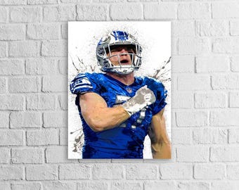 May include: A digital art print of a football player in a blue uniform and helmet. The artwork features a splash effect, with the player's arm raised in a gesture of triumph. The background is white.