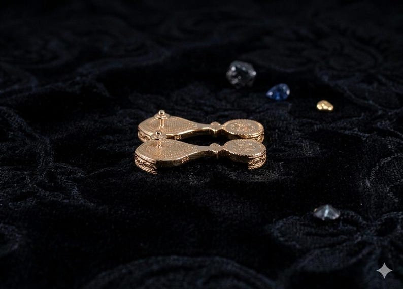 May include: A pair of gold-toned drop earrings featuring a teardrop-shaped top section connected to a circular bottom piece. The back of each earring displays a textured, patterned surface with a post and clutch closure, and the metal is stamped 925.