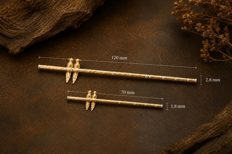 Puede incluir: Dos horquillas de metal dorado con superficie texturizada y un par de figuras de aves. La m&aacute;s larga mide 120 mm de largo y 2,8 mm de di&aacute;metro, mientras que la m&aacute;s corta mide 70 mm de largo y 1,8 mm de di&aacute;metro.