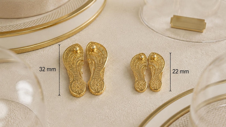 May include: Two pairs of gold-colored metal flip-flop charms with intricate embossed patterns. The larger pair measures 32 mm in length, while the smaller pair measures 22 mm in length. Each charm features a textured sole design and a small post.