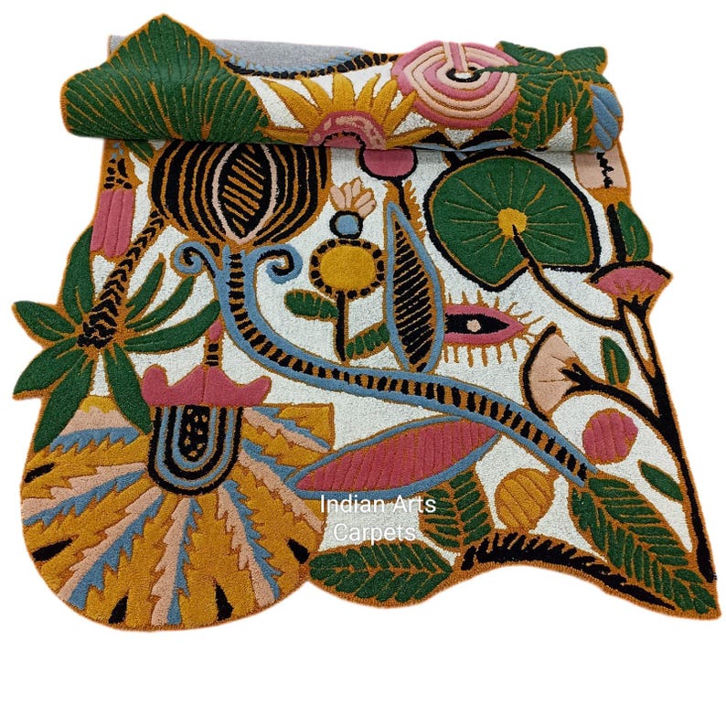 May include: A colorful, intricately designed rug with a white background and a variety of floral and leaf patterns in shades of green, yellow, pink, and blue. The rug features the text "Indian Arts Carpets".