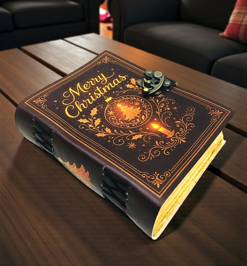May include: A decorative journal with a dark brown cover featuring the words "Merry Christmas" in gold script. The cover design includes a Christmas tree, candle, and holly leaves. The journal has a metal clasp and stitched binding.