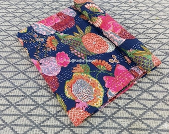 May include: A folded dark blue quilt featuring a vibrant floral and pineapple print in shades of pink, orange, green, and yellow. The fabric displays visible white running stitch details throughout the surface and includes the text Photo@KanthaTreasure.