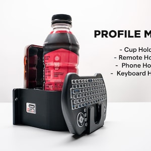 May include: Black profile mount with a cup holder, remote holder, phone holder, and keyboard holder. A bottle of red liquid and a phone are in the mount. The text "PROFILE MOUNT" is displayed in black, along with a list of the mount's features.