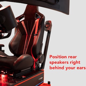 Può includere: Sedile nero e rosso per simulatore di corse con poggiatesta e altoparlanti integrati. Il sedile ha una base nera e dettagli rossi. Il testo nell'immagine dice: "Posiziona gli altoparlanti posteriori proprio dietro le tue orecchie".
