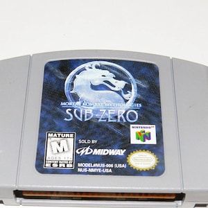 May include: A gray Nintendo 64 game cartridge for Mortal Kombat Mythologies: Sub-Zero. The cartridge has a blue and white label with the game title and a mature rating.