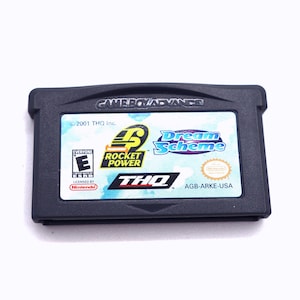 May include: A black Game Boy Advance game cartridge for Rocket Power: Dream Scheme. The game is rated E for Everyone by the ESRB. The cartridge has a blue and white background with the Rocket Power logo and the game title.