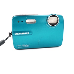 May include: A teal blue Olympus Stylus Water 3m/10ft waterproof digital camera with a black strap.