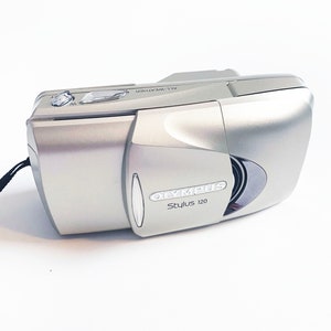 May include: A silver Olympus Stylus 120 point-and-shoot camera with the text "ALL-WEATHER" on the top.