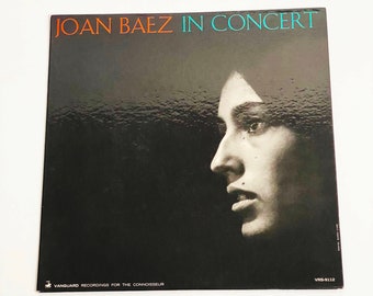 May include: A black and white photo of Joan Baez on the cover of a vinyl record. The record is titled "Joan Baez In Concert" and is a Vanguard recording for the connoisseur. The record number is VRS-9112.