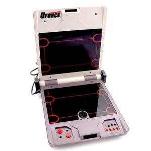 May include: A gray and black handheld video game console with a red UFORCE logo. The console has a built-in screen, a joystick, and buttons.