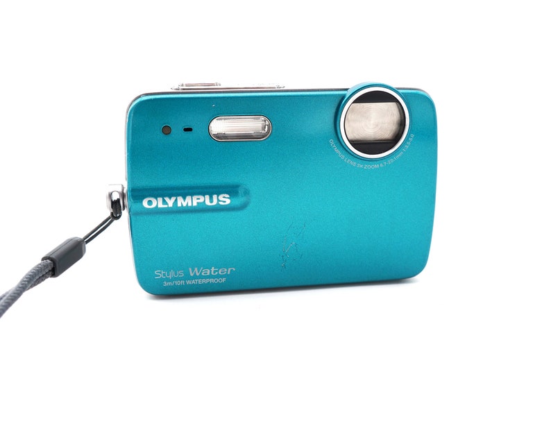 May include: A teal blue Olympus Stylus Water 3m/10ft waterproof digital camera with a black strap.