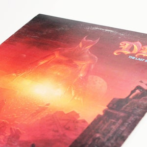 May include: A red and orange album cover with a large, shadowy figure in the center. The album title "DIO" and the subtitle "The Last in Line" are printed in white at the top of the cover.