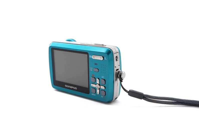 May include: A teal blue digital camera with a black strap. The camera has a screen, buttons, and the word "OLYMPUS" printed on the front.