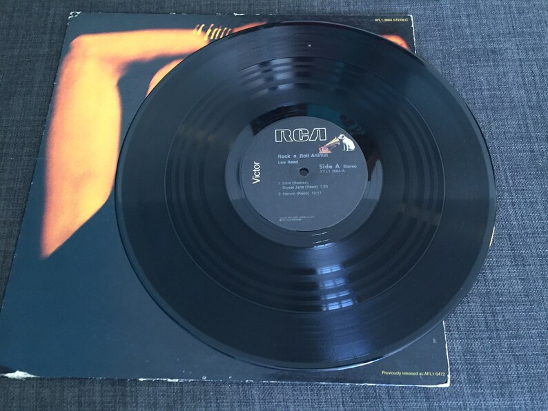 May include: A black vinyl record with a white label. The label has the text "RCA" in red, "Rock 'n' Roll Animal" in black, "Lou Reed" in black, "Side A:  Street Hassle" in black, "Victor" in black, and a list of songs with their lengths in black.