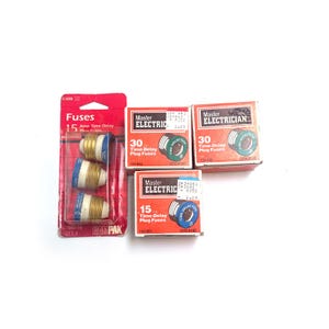 May include: A white ceramic mug with a black handle and the text "But First, Coffee" in a handwritten style. The mug is on a white surface. The mug is approximately 4 inches tall.