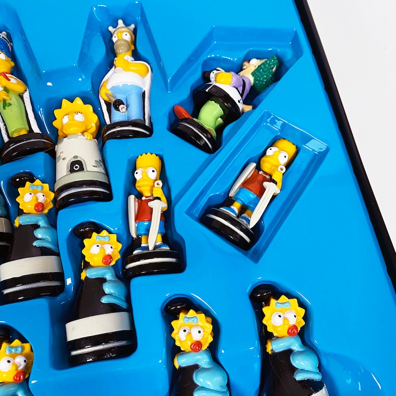 May include: A blue and yellow Simpsons chess set with various characters from the show, including Homer, Marge, Bart, Lisa, and Maggie. The chess pieces are made of plastic and are about 2 inches tall.