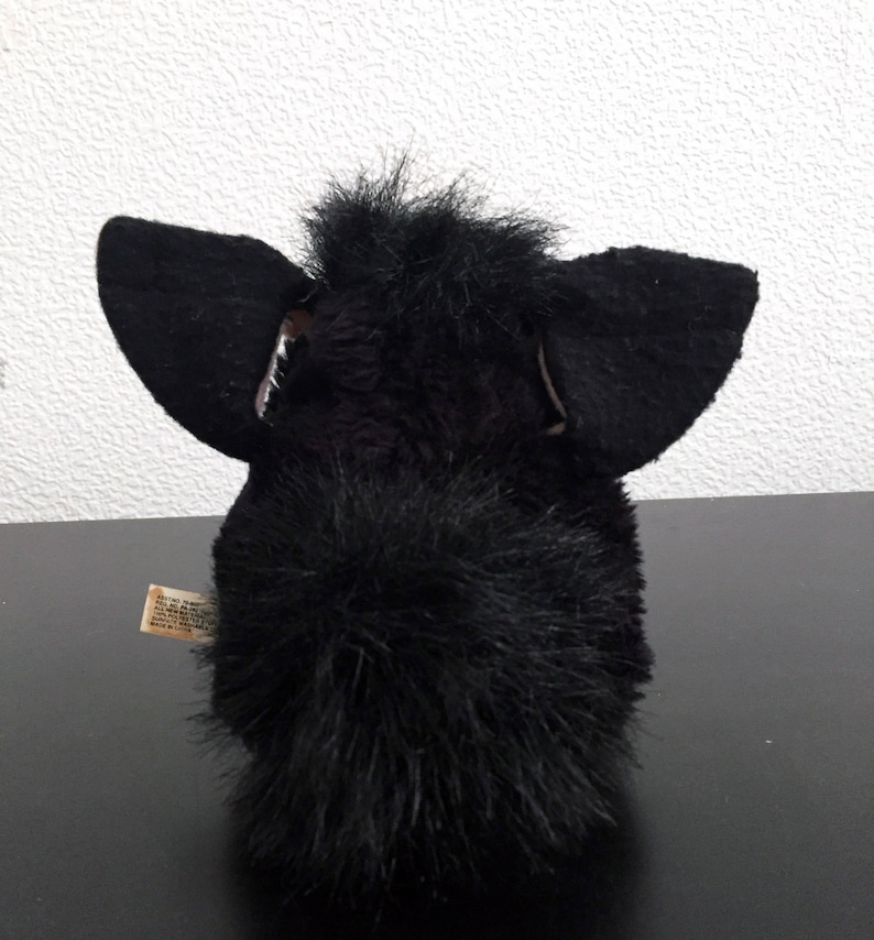 May include: Black furry toy with large ears and a long tail. The toy is made of soft, plush material.