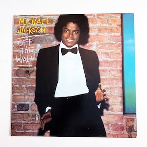 May include: A vintage vinyl record album cover featuring Michael Jackson in a black tuxedo with a white shirt and a black bow tie. The album title "Off the Wall" is written in yellow on a brick wall background.