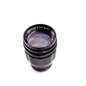 May include: A black Soligor Telephoto lens with the text "Soligor Telephoto" and "No.KA 103287" printed on the side.