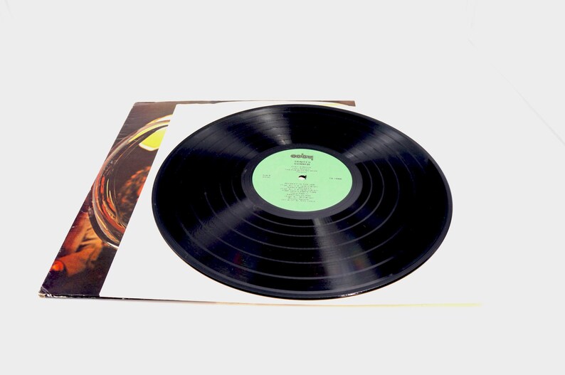 May include: A black vinyl record with a green label. The label has the text "Columbia" and "The Rolling Stones" in white. The record is on a white surface.