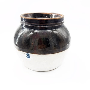 May include: A vintage stoneware crock with a dark brown glazed top and a white base. The crock has a rounded shape with a small handle and the number "3" in blue. This antique kitchenware is perfect for farmhouse decor.