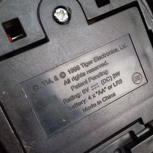 May include: Close-up of a black battery compartment with a label that reads: .TM. & &copy; 1998 Tiger Electronics, Ltd. All rights reserved. Patent Pending Rating: 6V (DC) 3W Battery: 4 x "AA" or LR6 Made in China