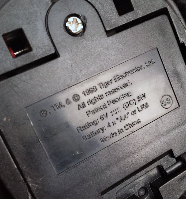 May include: Close-up of a black battery compartment with a label that reads: .TM. & &copy; 1998 Tiger Electronics, Ltd. All rights reserved. Patent Pending Rating: 6V (DC) 3W Battery: 4 x "AA" or LR6 Made in China