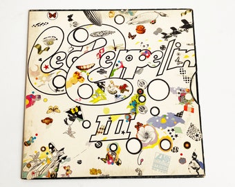 May include: A white album cover with the title "Led Zeppelin II" in black and white lettering. The cover features a colorful, abstract design with circles, stars, and other shapes.