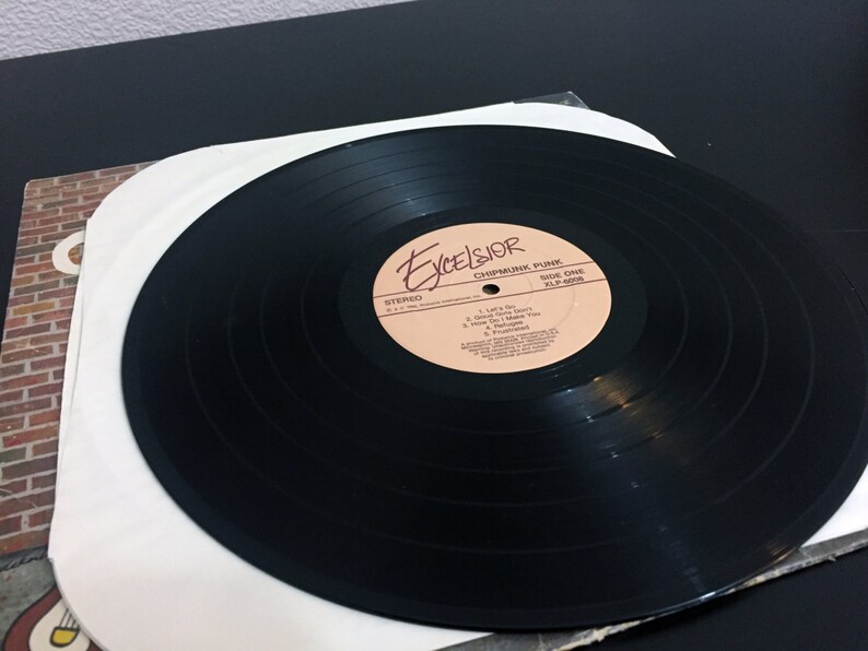 May include: Black vinyl record with a white paper inner sleeve. The record label is cream colored with brown text that reads "Excelsior Chipmunk Punk Side One XLP 8014". The track list includes "Let's Go", "I Don't Care", "How Do I Make You", "I'm Not Sure", "Frustrated".