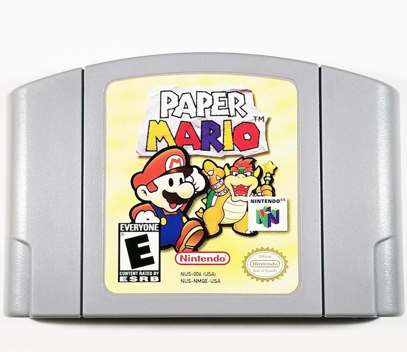May include: A silver Nintendo 64 game cartridge for Paper Mario. The front of the cartridge features a colorful illustration of Mario and a Koopa. The game is rated E for Everyone by the ESRB.