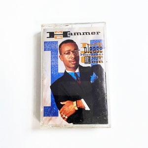 May include: A cassette tape featuring MC Hammer. The cover art features a portrait of MC Hammer in a black suit and blue tie. The text "Please Don't Hurt 'Em" is visible on the cover.
