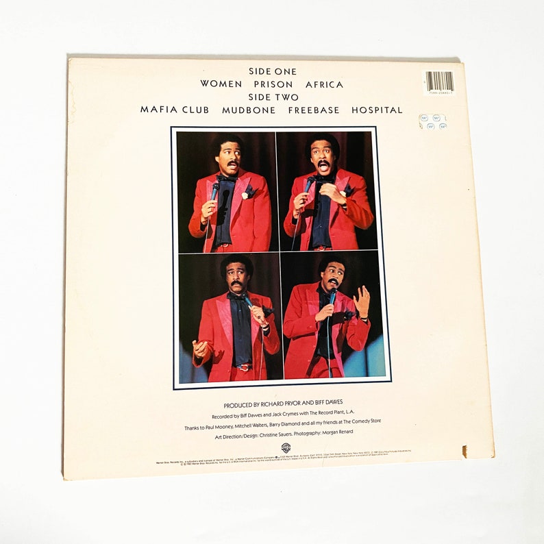 Puede incluir: Una portada de &aacute;lbum de vinilo vintage con el comediante Richard Pryor. La portada presenta cuatro fotos de Pryor con un traje rojo y corbata, actuando en el escenario. El t&iacute;tulo del &aacute;lbum es "Women Prison Africa" y "Mafia Club Mudbone Freebase Hospital".